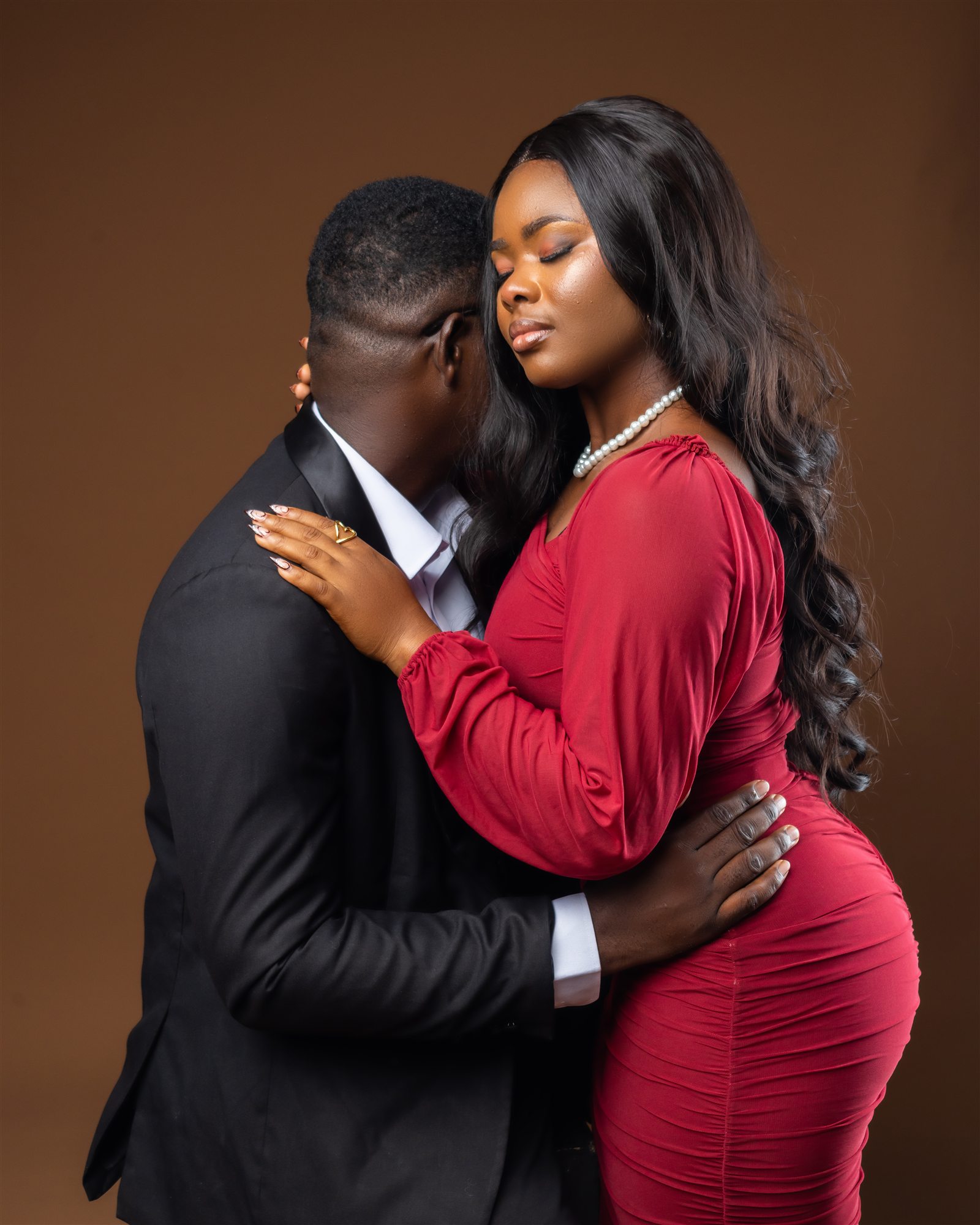 A couple in elegant evening wear sharing a close embrace.