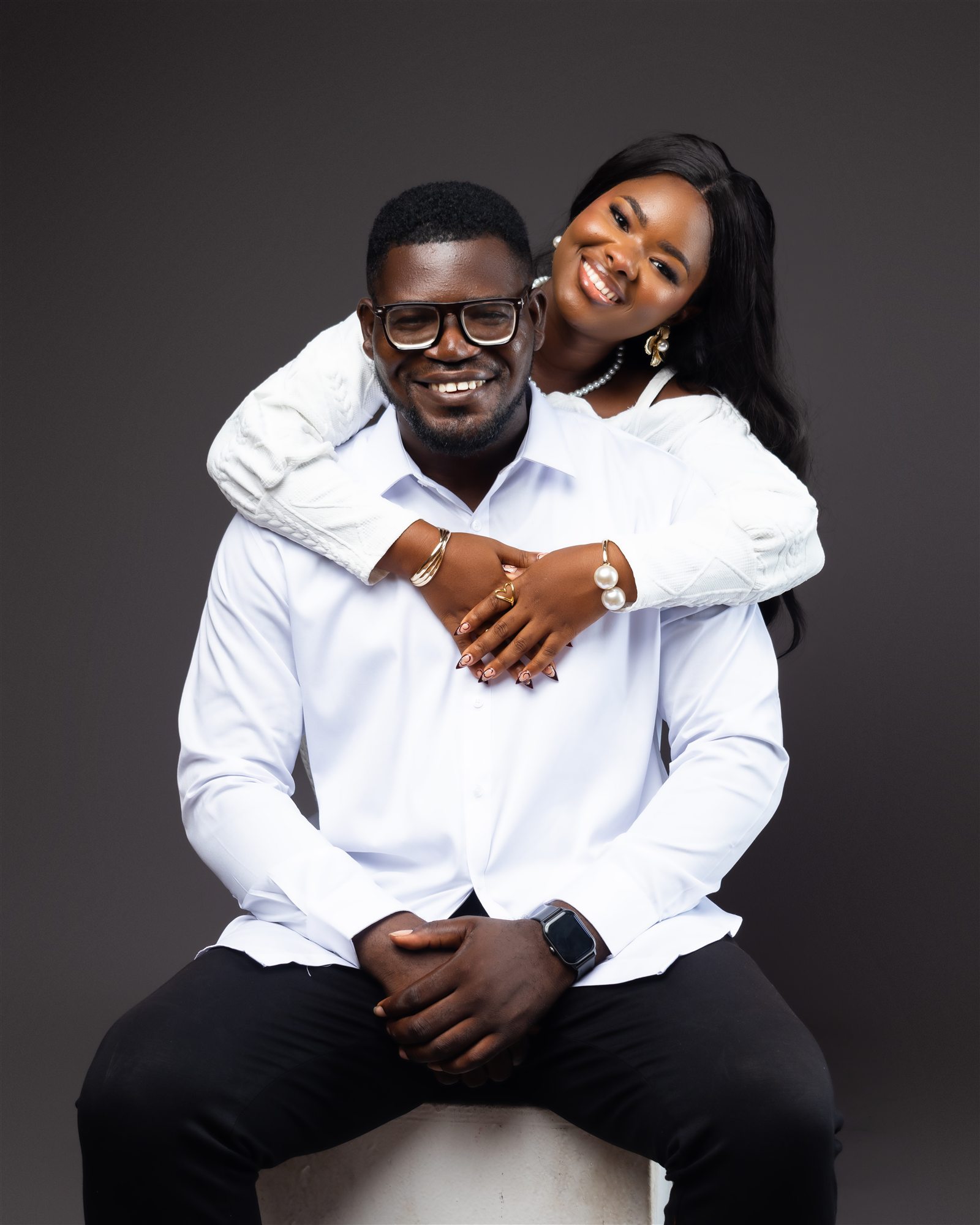 A couple dressed in white embracing in a studio portrait.