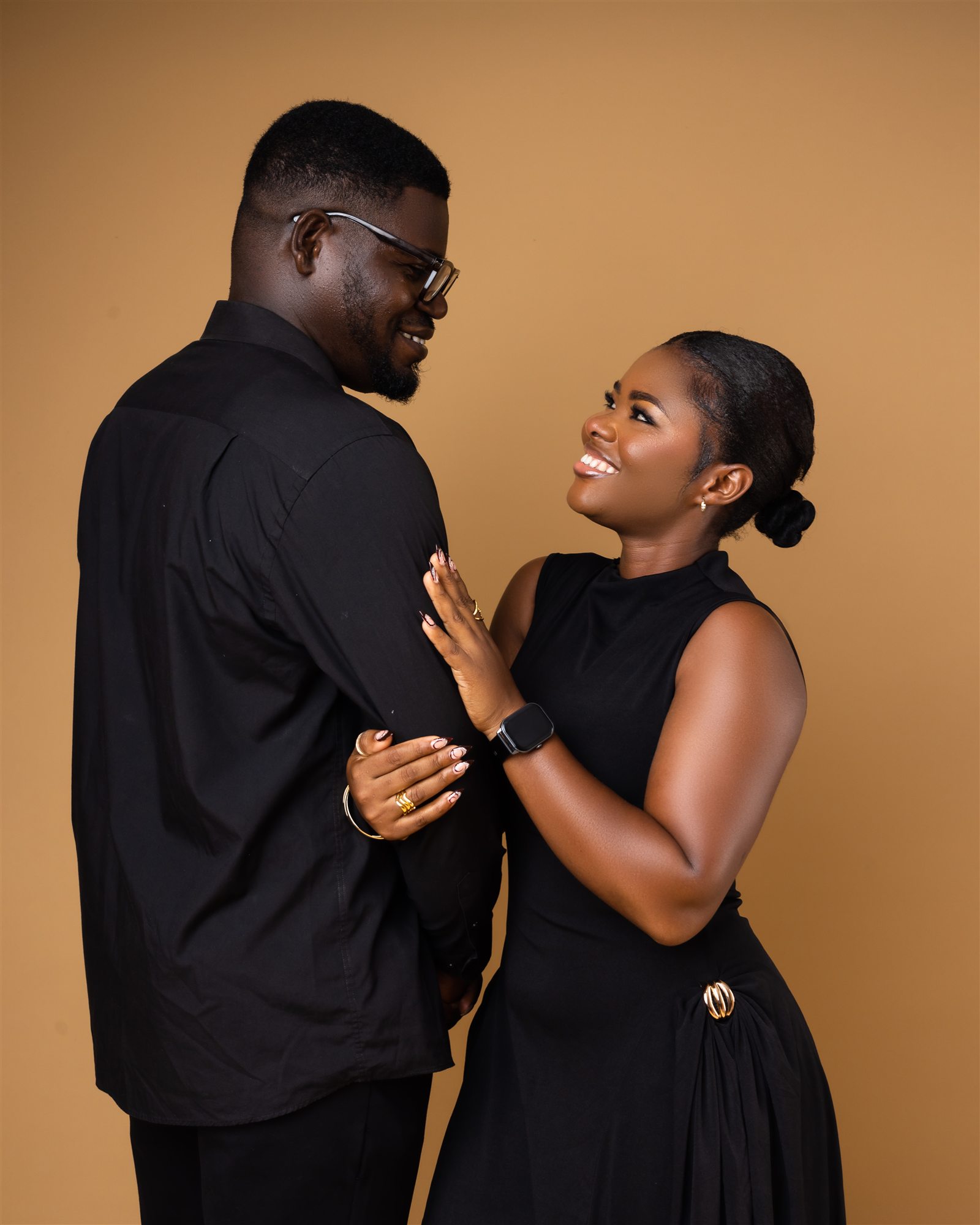 An engaged couple smiling warmly at each other.
